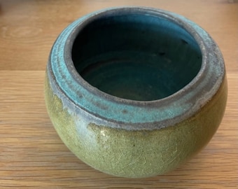 May include: A green and blue ceramic bowl with a crackled glaze. The bowl has a wide rim and a rounded bottom.