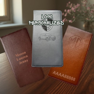 May include: Three rectangular leather checkbook covers in dark brown, gray, and tan. The brown cover features the names Mason, Lauren, and Jenny. The gray cover displays a car graphic and the text LOGO PERSONALIZED. The tan cover shows an MG logo and AAAA88888.