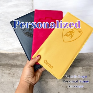 Puede incluir: Tres carteras de cuero personalizadas en azul marino, fucsia y amarillo. Cada cartera presenta un logotipo de vehículo y la palabra "Personalizado" en letra cursiva. La cartera amarilla tiene el nombre "Gene" impreso.