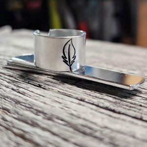 May include: Silver metal bookmark with a feather design. The bookmark has a ring to hold a page.