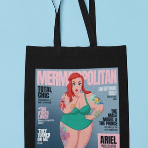 May include: A black tote bag with a magazine print featuring a cartoon illustration of Ariel from The Little Mermaid. The magazine cover is titled "Mermopolitan" and features the text "Total Chic", "The Other Lover", "They Turned On Me", "Unfortunate Soul?", "The Male Model & The Prince", and "Ariel Wants The Haters To Kiss Her Feet".