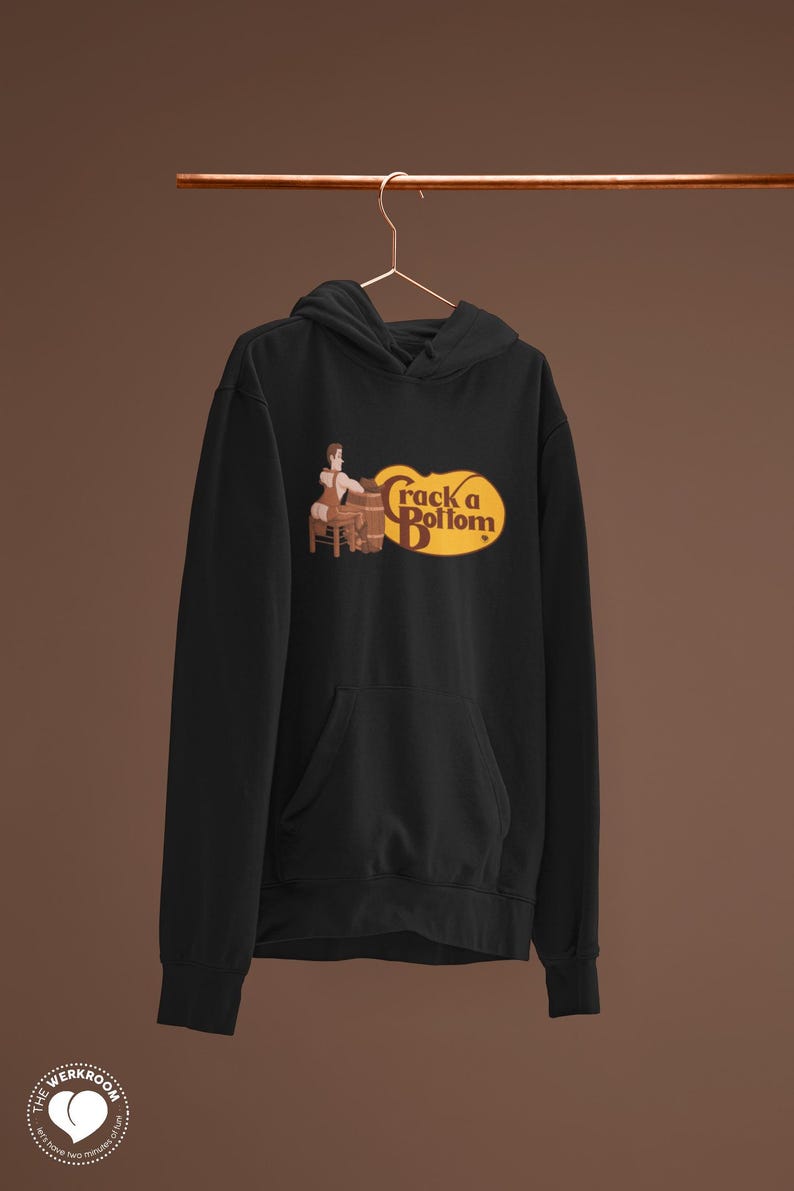 May include: Black hooded sweatshirt with a front pocket and a graphic that reads "Crack a Bottom" in a yellow oval. The graphic features a cartoon of a person sitting on a barrel. The Werkroom logo is visible on the bottom left.