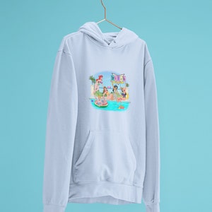 Może przedstawiać: Jasnoniebieska bluza z kapturem z grafiką przedstawiającą imprezę przy basenie. Ilustracja przedstawia kobiety w strojach kąpielowych przy basenie, z napisem "Bitch" na znaku. Bluza ma kieszeń typu kangur i kaptur ze sznurkiem.