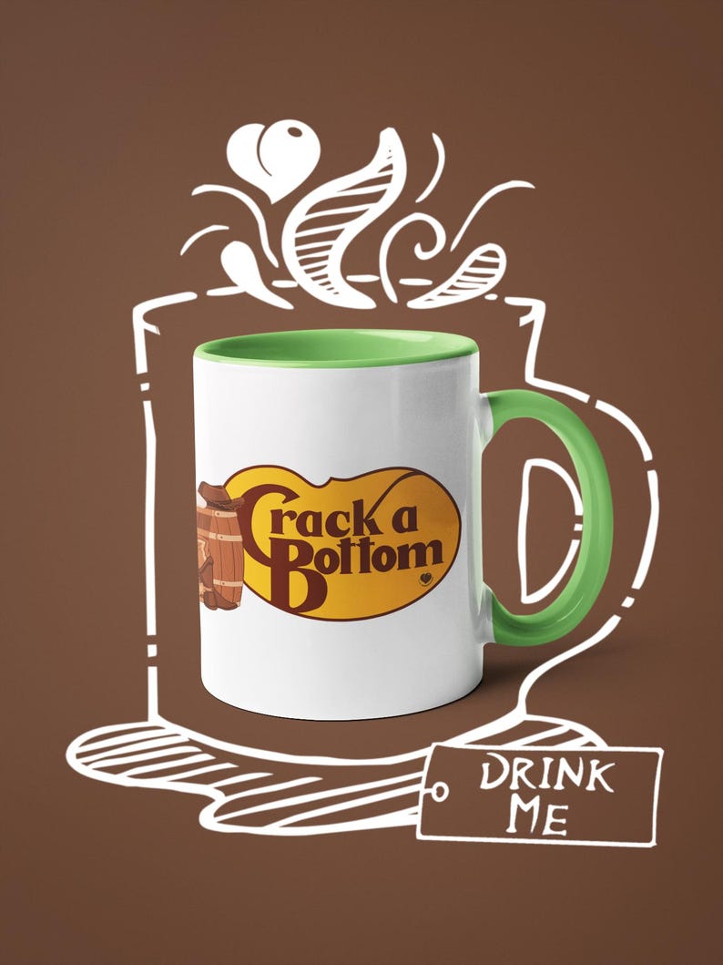 Op de afbeelding: Witte keramische mok met een groene handgreep en binnenkant, met de tekst "Crack a Bottom" in bruin en geel. De mok staat tegen een bruine achtergrond met een witte omtrek van een koffiekopje en de woorden "DRINK ME".