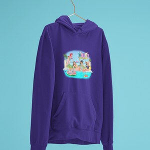 Może przedstawiać: Fioletowa bluza z kapturem z nadrukiem na przodzie przedstawiającym scenę przy basenie z kobietami, basenem i napisem "Beach". Bluza ma kaptur i przednią kieszeń. Tło jest jasnoniebieskie.