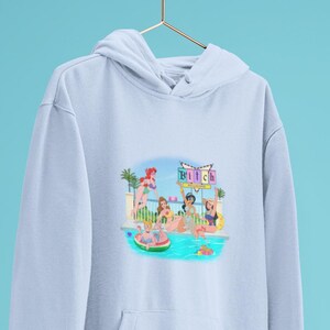 Może przedstawiać: Jasnoniebieska bluza z kapturem z grafiką postaci z kresk&oacute;wek przy basenie, z napisem "Bitch" na znaku. Ilustracja przedstawia kobiety w strojach kąpielowych z palmami w tle.