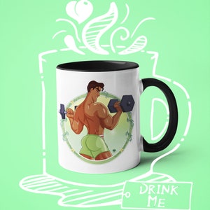 May include: A white ceramic mug with a black handle and rim. The mug features a colorful illustration of a person lifting weights. The text "Drink Me" is written on a tag hanging from the mug.