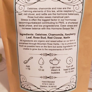May include: A blue and white label with a floral design. The label lists the ingredients of a tea blend: Oatstraw, Chamomile, Raspberry Leaf, Rose Bud, Red Clover, and Nettle. The label also includes instructions for brewing the tea: add 1 tablespoon of tea to 12 ounces of water, bring to a light boil, and steep for 10-15 minutes.