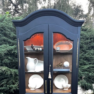 Black arched cabinet, double beveled glass doors, custom white oak backing, shelves and base. Comes with working key. Vintage. One of a kind