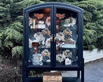 Black, vintage, arched cabinet with double glass doors and decorative wallpaper. Custom legs with  shelf. One of a kind!