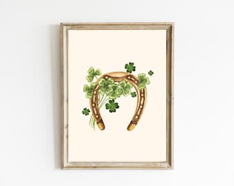 May include: A gold horseshoe with green four-leaf clover accents. The horseshoe is surrounded by a cluster of clovers, creating a festive St. Patrick's Day design.