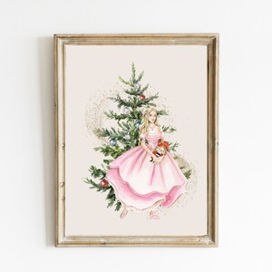 Puede incluir: Una pintura de acuarela de una joven con un vestido rosa de pie junto a un árbol de Navidad decorado. Ella está sosteniendo un cascanueces en sus brazos. El fondo es de color beige claro.