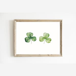 May include: A framed print with two watercolor illustrations of shamrocks, one green and one light green.