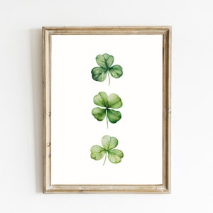 May include: A framed print of three watercolor shamrocks, each with four green leaves, arranged vertically in a row.