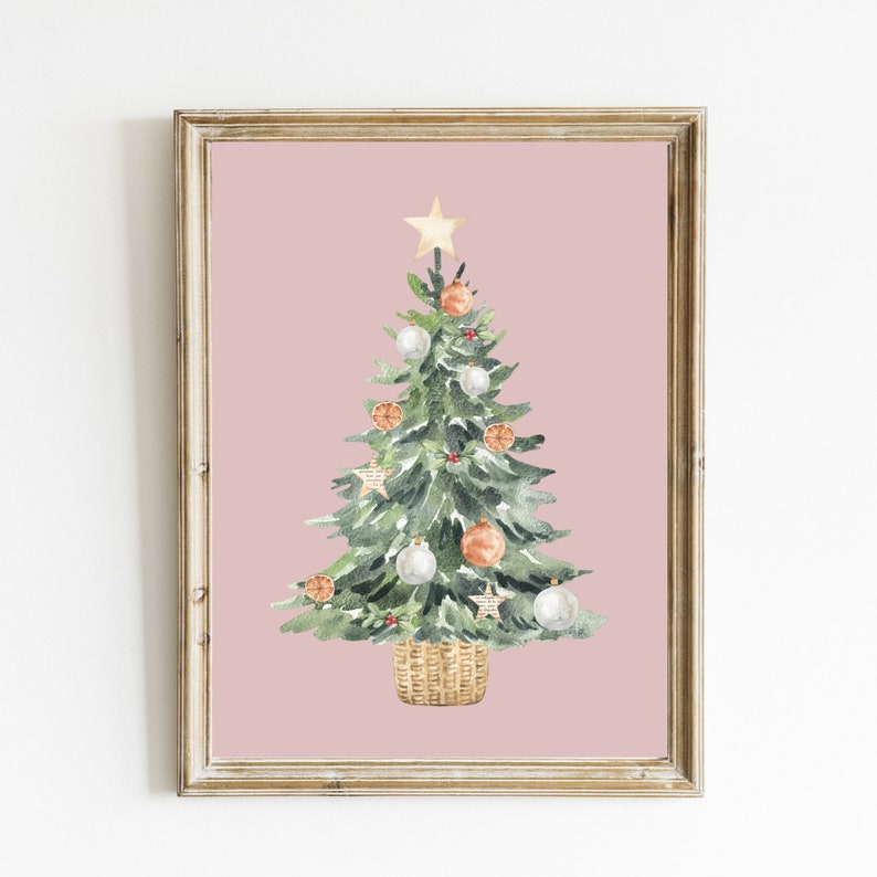 K&ouml;nnte beinhalten: Ein Aquarellbild eines Weihnachtsbaums vor rosa Hintergrund. Der Baum ist mit wei&szlig;en und orangen Kugeln, einem goldenen Stern oben und einem braunen Weidenkorb am Fu&szlig; geschm&uuml;ckt.