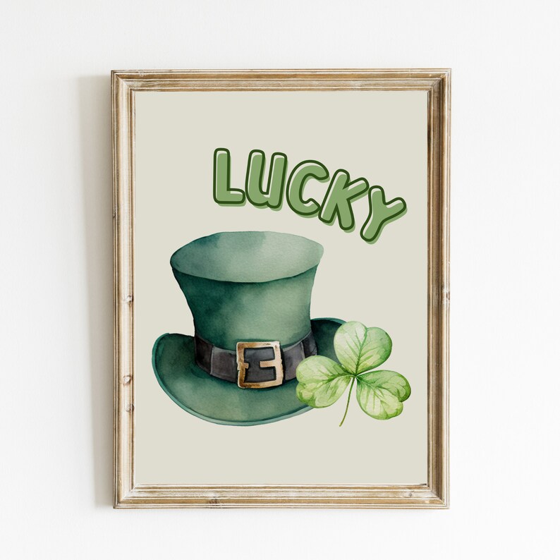 May include: A printable art print with a green leprechaun hat and a four-leaf clover. The text "LUCKY" is written in green letters.