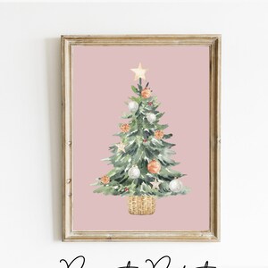 K&ouml;nnte beinhalten: Ein Aquarellbild eines Weihnachtsbaums vor rosa Hintergrund. Der Baum ist mit wei&szlig;en und orangen Kugeln, einem goldenen Stern oben und einem Korb an der Basis geschm&uuml;ckt. Der Text "Paper to Perfect printable art collection" befindet sich unter dem Bild.