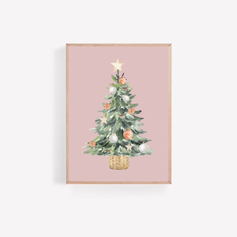 K&ouml;nnte beinhalten: Ein Aquarellbild eines Weihnachtsbaums vor rosa Hintergrund. Der Baum ist mit wei&szlig;en und orangefarbenen Kugeln, einem goldenen Stern oben und einem braunen Weidenkorb an der Basis geschm&uuml;ckt.