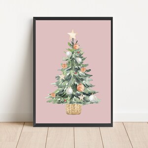K&ouml;nnte beinhalten: Ein Aquarellbild eines Weihnachtsbaums vor rosa Hintergrund. Der Baum ist mit wei&szlig;en und orangefarbenen Kugeln, einem Stern oben und einem braunen Weidenkorb geschm&uuml;ckt.