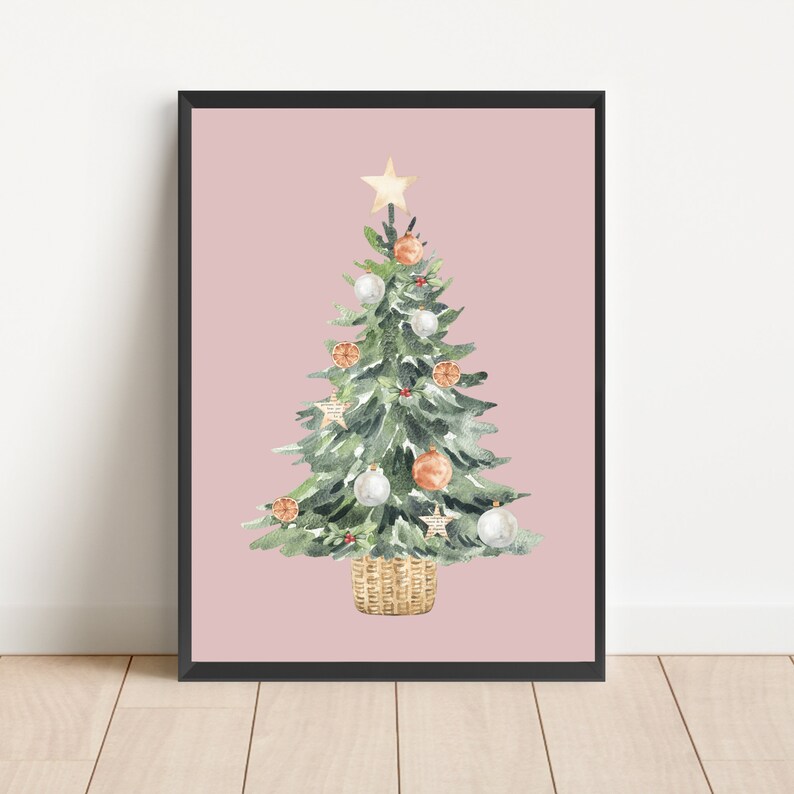 K&ouml;nnte beinhalten: Ein Aquarellbild eines Weihnachtsbaums vor rosa Hintergrund. Der Baum ist mit wei&szlig;en und orangefarbenen Kugeln, einem Stern oben und einem braunen Weidenkorb geschm&uuml;ckt.