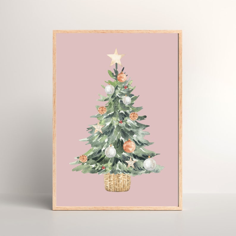 K&ouml;nnte beinhalten: Ein Aquarellbild eines Weihnachtsbaums vor rosa Hintergrund. Der Baum ist mit wei&szlig;en und orangefarbenen Kugeln, einem goldenen Stern oben und einem braunen Weidenkorb an der Basis geschm&uuml;ckt.