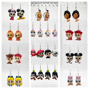 May include: A display of 18 pairs of dangle earrings featuring various Disney characters. The earrings are made of metal and have a variety of colors and designs. The characters include Mickey Mouse, Minnie Mouse, Aladdin, Jasmine, Ariel, Ursula, and more.