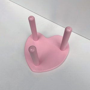 Peut inclure: Un support en bois en forme de c&oelig;ur rose avec trois chevilles en bois. Le support est parfait pour exposer de petits objets.