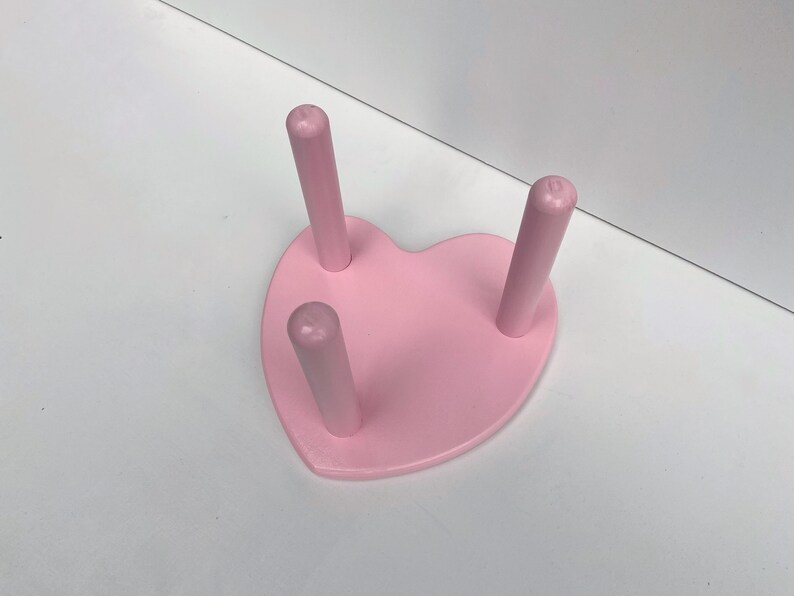 Peut inclure: Un support en bois en forme de c&oelig;ur rose avec trois chevilles en bois. Le support est parfait pour exposer de petits objets.