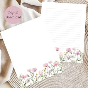 以下が含まれることがあります： 花柄のデザインが施された白い便箋が2枚。各シートの下部には、緑の茎と葉を持つピンク、紫、黄色の花が描かれています。1枚のシートには横線があり、もう1枚にはピンクの円の中に「Digital Download」という文字があります。
