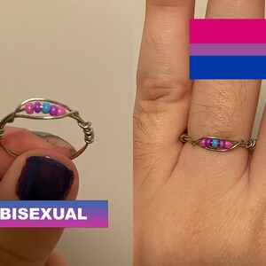 May include: A silver ring with pink, purple, and blue beads, representing the bisexual pride flag.