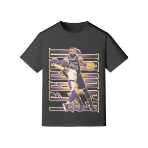 May include: Black crew neck t-shirt with a graphic of a basketball player in a Lakers uniform. The design includes the player's image and the word "JAMES" in a stylized font, with purple and gold accents.