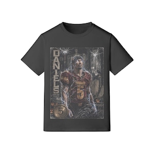 May include: A black short-sleeved t-shirt featuring a graphic print of a football player wearing a burgundy jersey with the number 5. The design includes the text DANIELS, LIGHTS OUT, WASHINGTON, and a dark, stormy background with lightning effects.