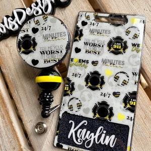 May include: A white and black firefighter themed badge holder with a black glitter name tag that says "Kaylin". The badge holder has a black and yellow striped retractable badge reel with a black and yellow firefighter emblem. The badge holder has the text "24/7 Minutes Matter" and "Tell me your worst I'll send the best" repeated on it.