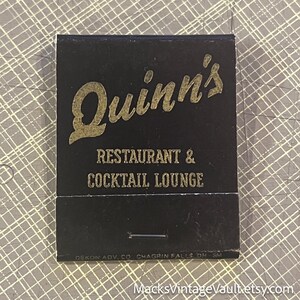 May include: A vintage matchbook with a black cover and gold lettering. The text reads "Quinn's RESTAURANT & COCKTAIL LOUNGE." The bottom of the matchbook has the text "DEKON ADV. CO CHAGRIN FALLS DH-SM."