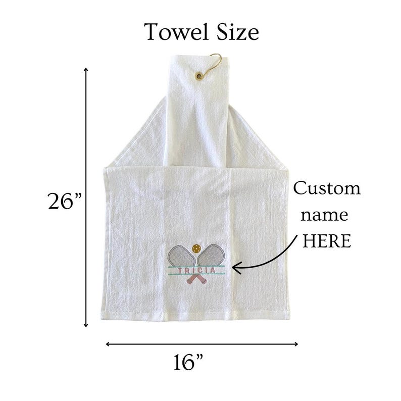 May include: White hanging towel with a tennis-themed embroidered design. The towel measures 26 inches long and 16 inches wide. The design includes tennis rackets, a tennis ball, and the name "TRICIA". The text "Custom name HERE" is also visible.