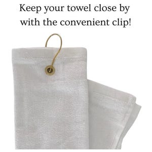 May include: White towel with a gold-colored clip. The towel is folded and has a loop for hanging. Text on the image reads: Keep your towel close by with the convenient clip!