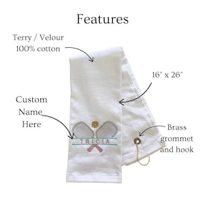May include: White terry cloth towel, 16" x 26", with embroidered tennis rackets, a tennis ball, and the name "TRICIA". Features a brass grommet and hook. Made of 100% cotton.