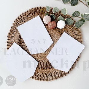 Puede incluir: Tres pancartas blancas en blanco de 12,7 x 17,8 cm en una base de paja tejida con calabazas decorativas. El texto "FLAG BANNER MOCKUP" está impreso en gris en la base.
