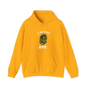 May include: A yellow hoodie with a white graphic of a camouflage ape head and the text "A Bathing Ape" on the front.