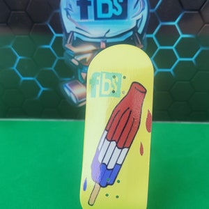 May include: Yellow fingerboard with a red, white, and blue popsicle graphic. The popsicle is dripping red and has a wooden stick. The fingerboard has the text "FBS" on it.