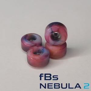 May include: Four multi-colored skateboard wheels with a nebula design. The wheels are primarily pink, blue, and purple, with a silver metal core. The text "fBs NEBULA 2" is printed at the bottom.