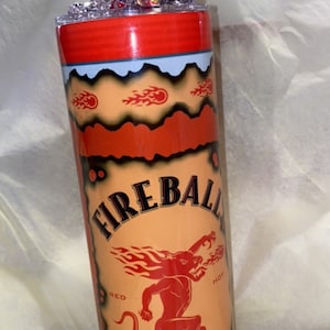 Op de afbeelding: Een aangepaste tumbler met het Fireball Cinnamon Whisky-merk. Het ontwerp bevat de merknaam, een rode duivelafbeelding en vlamaccenten. Een miniatuur Fireball-fles is boven de tumbler geplaatst.