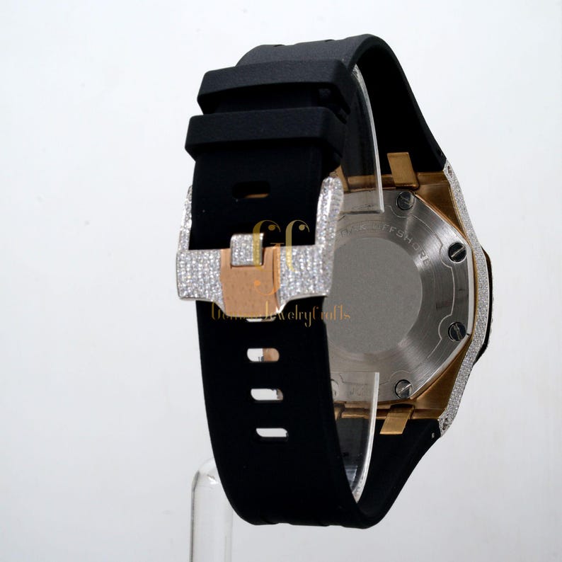 May include: A black rubber strap watch with a diamond-encrusted bezel and rose gold accents. The watch has a stainless steel case and a black dial. The watch is shown from the back.