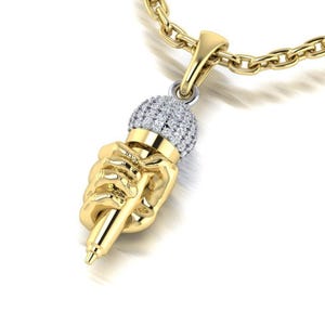 May include: A gold pendant necklace featuring a hand holding a microphone with a diamond-encrusted head.
