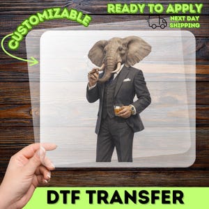 May include: A DTF transfer sheet featuring a graphic of an elephant with a human body wearing a dark grey three-piece suit, holding a lit cigar in its trunk and a glass of amber liquid in one hand, set against a plain white background.