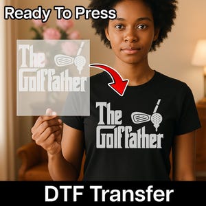 May include: Black t-shirt with the text "The Golf Father" in white, along with a golf club and ball graphic. The words "Ready To Press" are at the top, and "DTF Transfer" at the bottom.