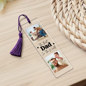 May include: A clear acrylic bookmark with a purple tassel. The bookmark features two photos of a father and his children. The text on the bookmark reads "The Best Dad In The World".