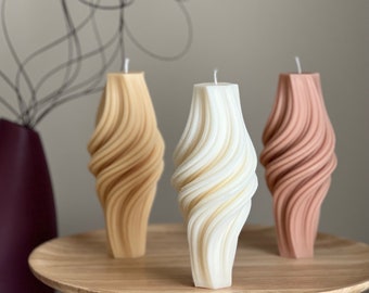 May include: Three decorative candles with a swirling, textured design. The candles are in shades of beige, cream, and light pink.