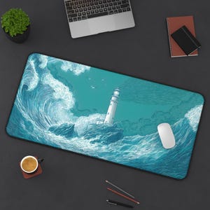 Pode incluir: Tapete de secretária retangular com uma ilustração detalhada de um farol numa ilha rochosa, rodeado por ondas a quebrar. O design é em tons de azul e branco. Um rato e outros materiais de escritório são visíveis.