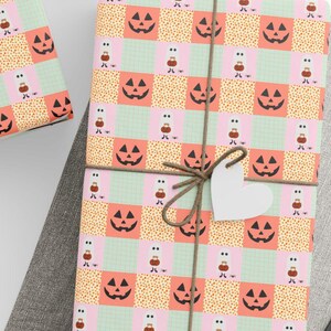 Peut inclure: Plusieurs cadeaux emballés avec du papier cadeau sur le thème d'Halloween. Le papier présente un motif patchwork avec des visages de jack-o'-lantern, de petites figures et des pois orange, roses et verts. Chaque cadeau est noué avec de la ficelle et une étiquette blanche.